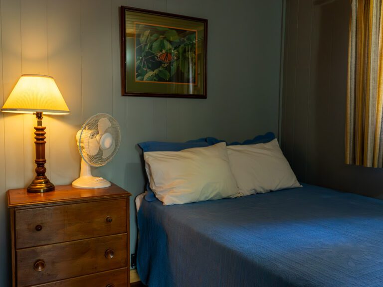 A cottage bedroom, with the nightstand lamp on