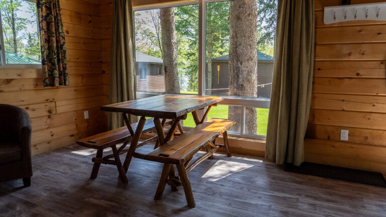 Cabin interior, with table in front of sliding glass doors looking out onto grounds